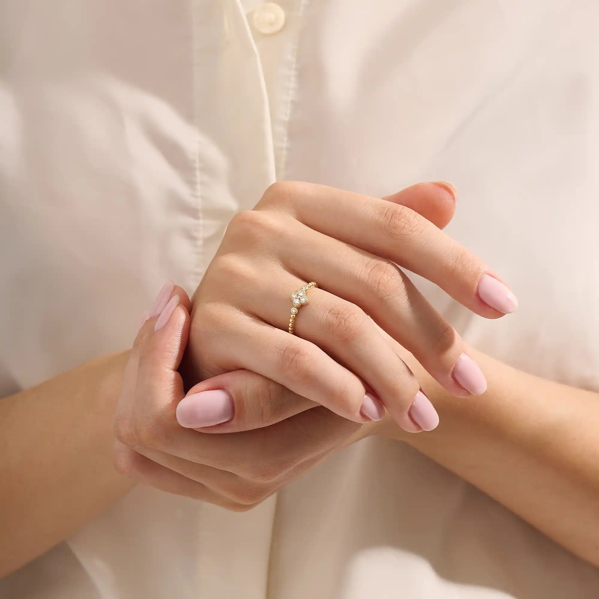 Model wears a 14k gold pinky signet ring featuring a clover-shaped moissanite and textured beaded band. Elegant and meaningful everyday jewelry.