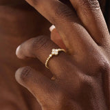 Model wears a 14k gold pinky signet ring featuring a clover-shaped moissanite and textured beaded band. Elegant and meaningful everyday jewelry.