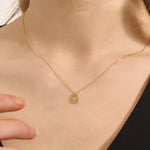 Model wears a 14k gold rectangle necklace with a dangling personalized letter charm. Sleek and meaningful jewelry perfect for layering.