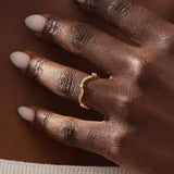 Model wears a 14k gold stacking ring with a wavy ups and downs design. Ideal for stacking or wearing solo with subtle texture.