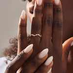 Model wears a 14k gold stacking ring with a wavy ups and downs design. Ideal for stacking or wearing solo with subtle texture.
