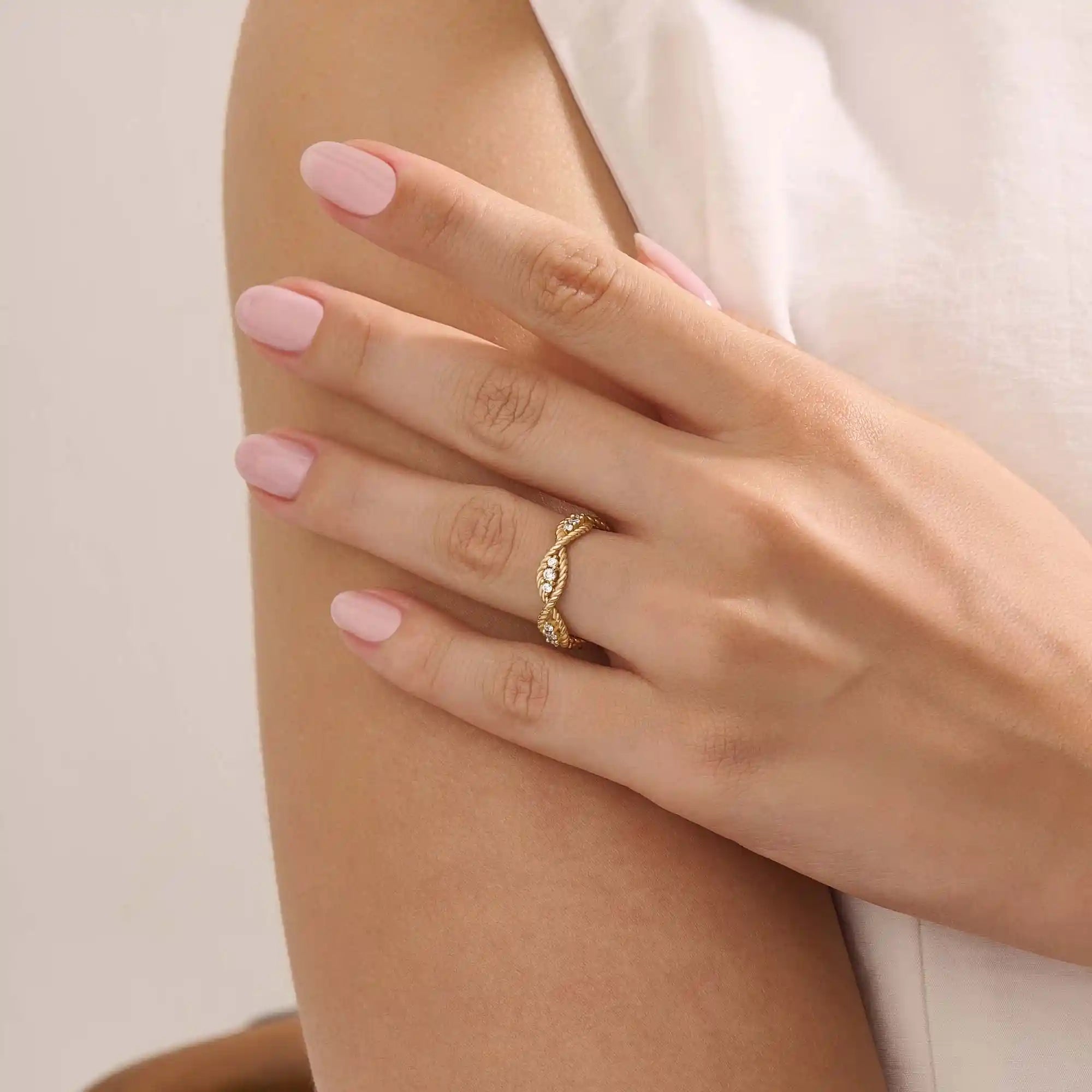 Model wears a 14k gold twisted band eternity ring featuring moissanite accents. A stylish and timeless statement piece for everyday wear.