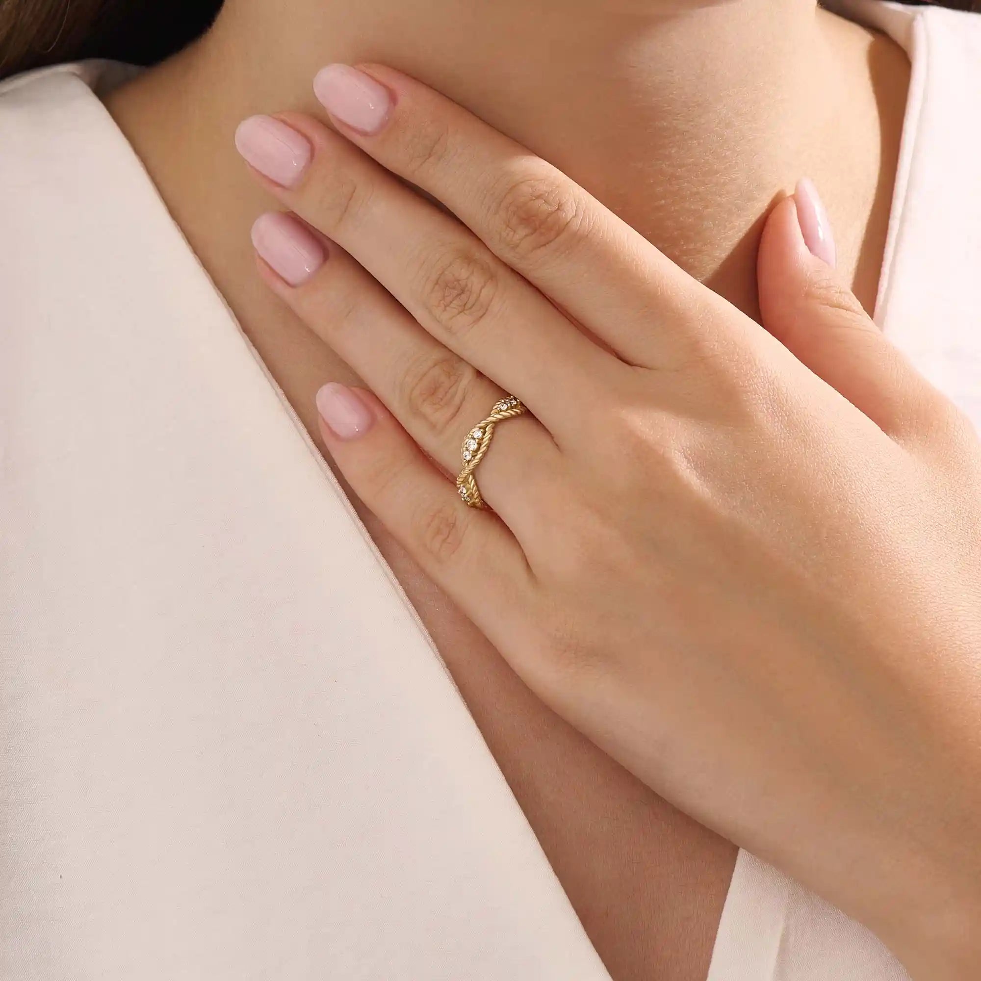 Model wears a 14k gold twisted band eternity ring featuring moissanite accents. A stylish and timeless statement piece for everyday wear.