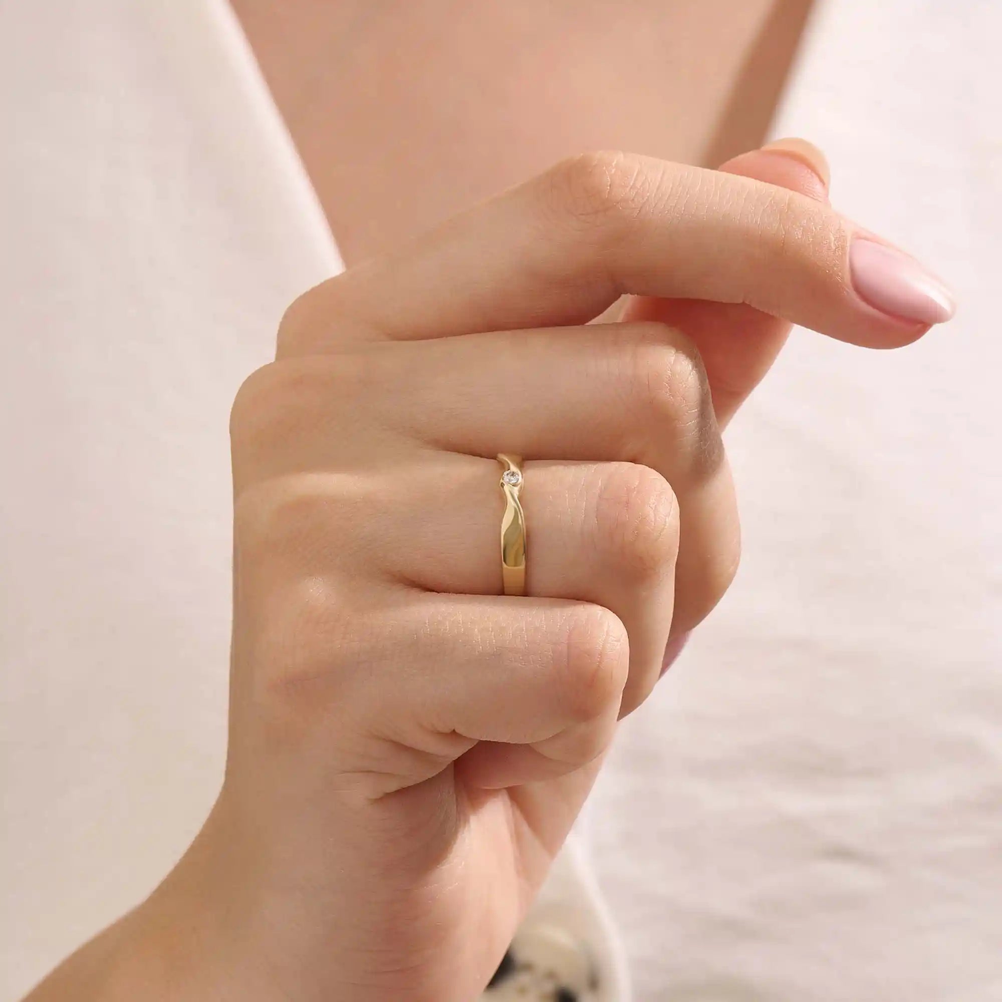 Model wears a 14k gold twisted band promise ring featuring a single bezel-set moissanite. A sleek and stylish symbol of commitment.