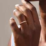 Model wears a 14k gold two-sided wedding ring featuring leaf engravings and channel-set moissanites. Perfect for a distinctive and meaningful wedding band.