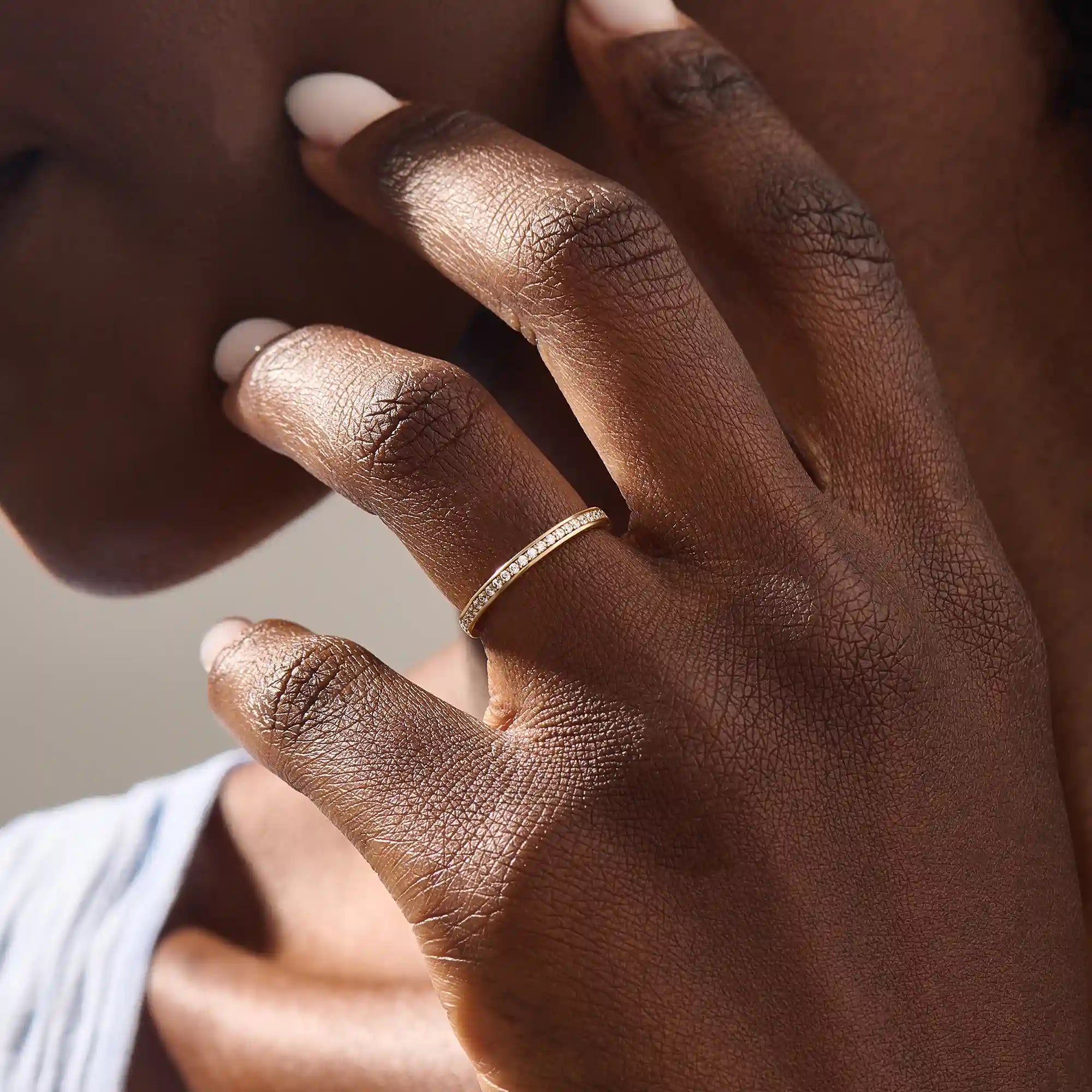 Model wears a 14k gold two-sided wedding ring featuring leaf engravings and channel-set moissanites. Perfect for a distinctive and meaningful wedding band.