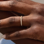 Model wears a 14k gold two-sided wedding ring featuring leaf engravings and channel-set moissanites. Perfect for a distinctive and meaningful wedding band.
