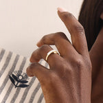 Model wears a 14k gold wrap-around spiral statement ring featuring baguette half eternity moissanites. Bold and stylish everyday accessory.