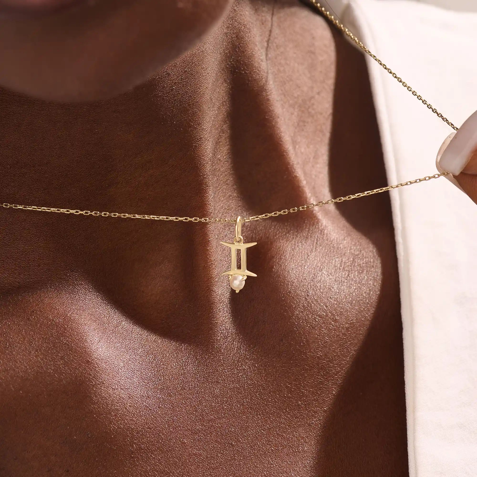 Model wears a 14k solid gold Gemini zodiac symbol pendant necklace with a natural pearl, perfect for astrology lovers.