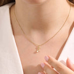 Model wears a 14k solid gold Gemini zodiac symbol pendant necklace with a natural pearl, perfect for astrology lovers.