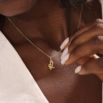 Model wears a 14k solid gold Leo zodiac symbol pendant necklace with green peridot, perfect for Leo zodiac birthdays.