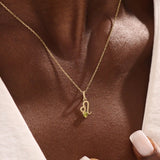 Model wears a 14k solid gold Leo zodiac symbol pendant necklace with green peridot, perfect for Leo zodiac birthdays.
