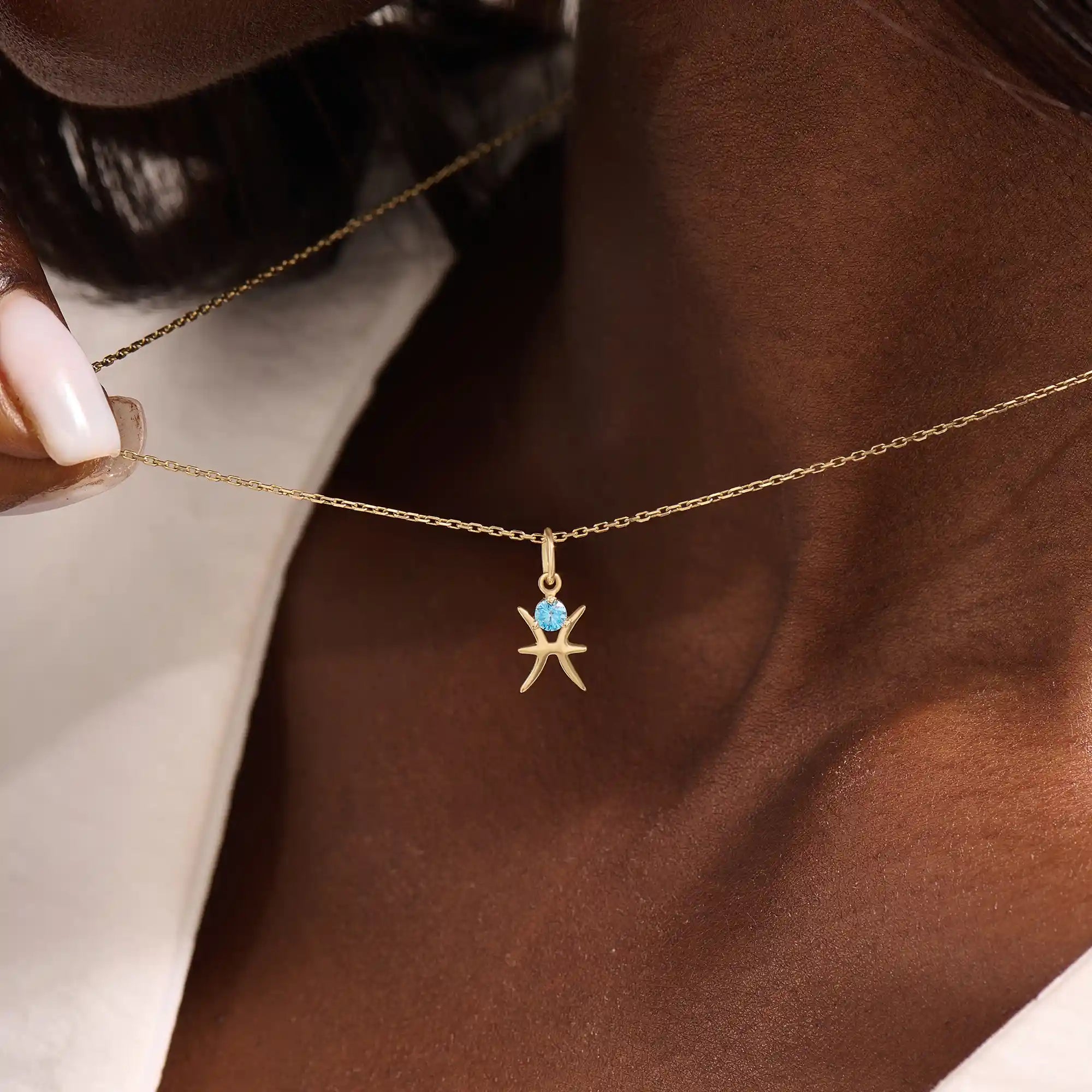 Model wears a 14k solid gold Pisces zodiac symbol pendant necklace with aquamarine, perfect for Pisces zodiac birthdays.