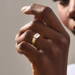 Model wears a 14k solid gold chunky Toi et Moi engagement ring with prong-set emerald-cut and half bezel-set round moissanites. Unique and striking statement piece for brides.