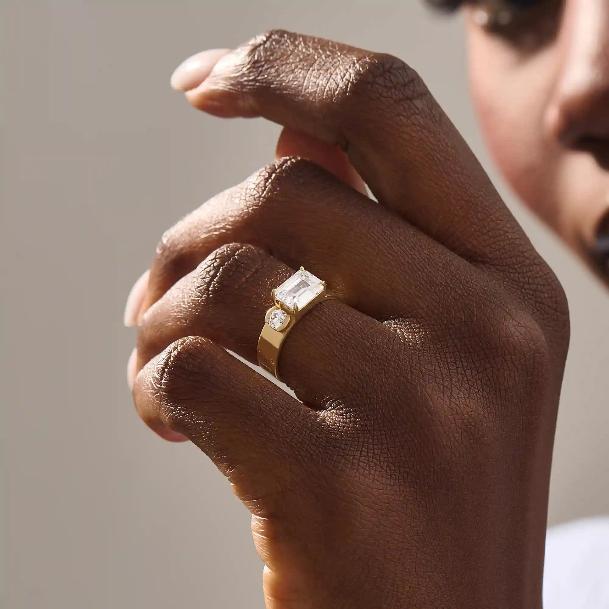 Model wears a 14k solid gold chunky Toi et Moi engagement ring with prong-set emerald-cut and half bezel-set round moissanites. Unique and striking statement piece for brides.