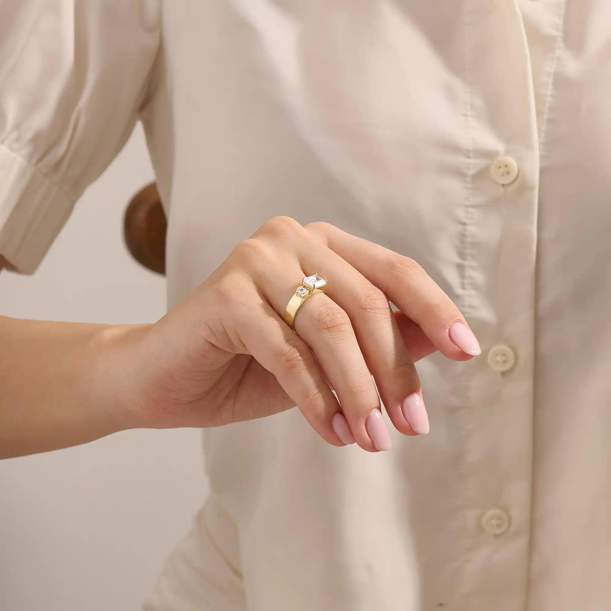 Model wears a 14k solid gold chunky Toi et Moi engagement ring with prong-set emerald-cut and half bezel-set round moissanites. Unique and striking statement piece for brides.