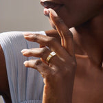 Model wears a 14k solid gold chunky Toi et Moi engagement ring with prong-set emerald-cut and half bezel-set round moissanites. Unique and striking statement piece for brides.