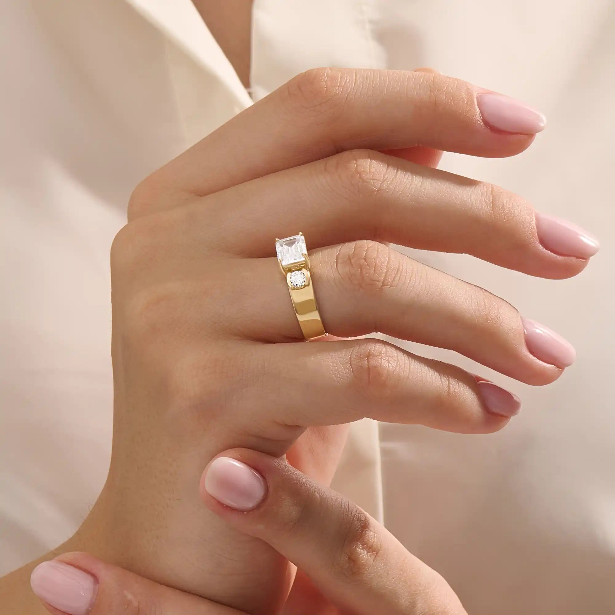 Model wears a 14k solid gold chunky Toi et Moi engagement ring with prong-set emerald-cut and half bezel-set round moissanites. Unique and striking statement piece for brides.