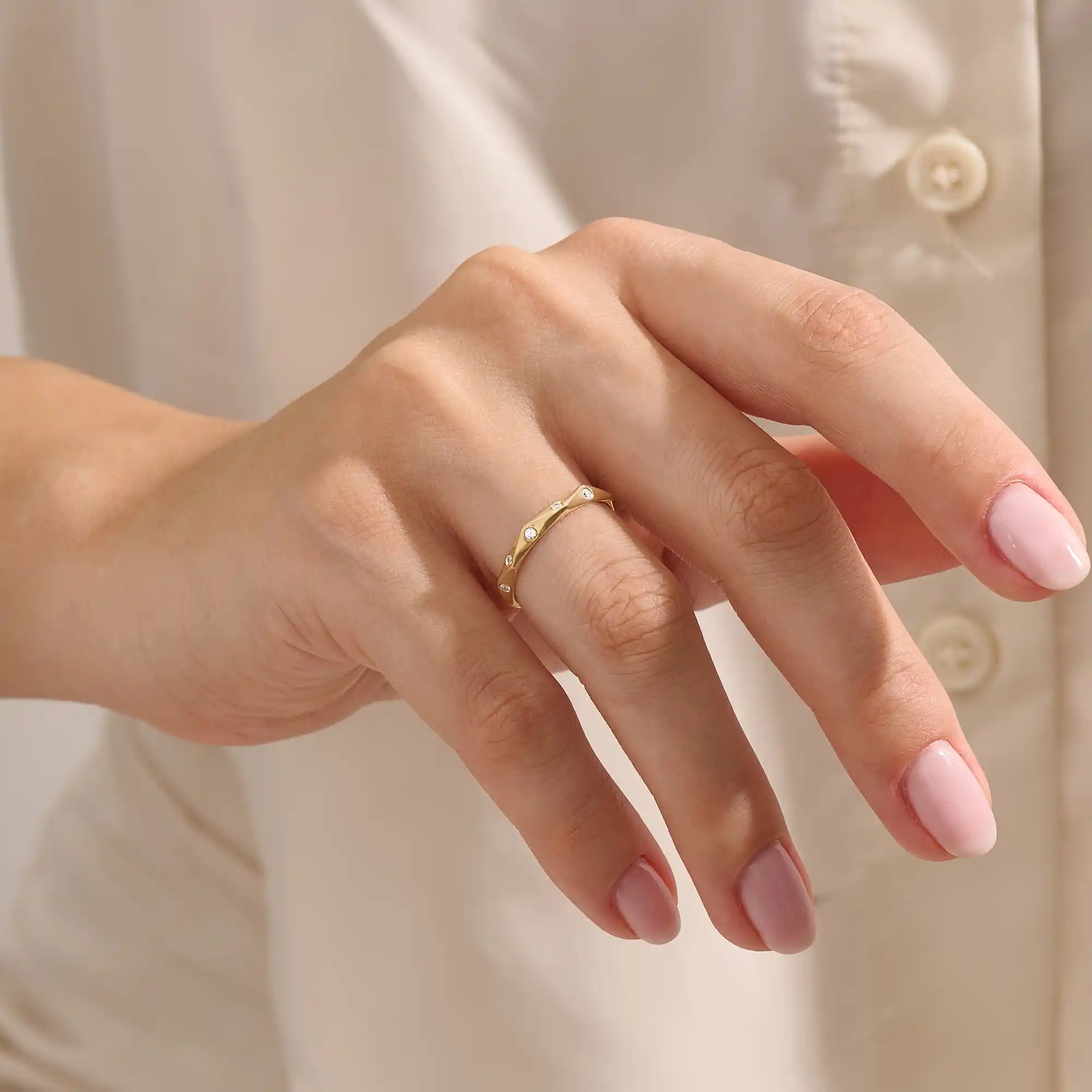 Model wears a 14k solid gold faceted band wedding ring featuring tiny moissanites. Elegant and versatile style for stacking or bridal jewelry.