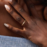 Model wears a 14k solid gold faceted band wedding ring featuring tiny moissanites. Elegant and versatile style for stacking or bridal jewelry.
