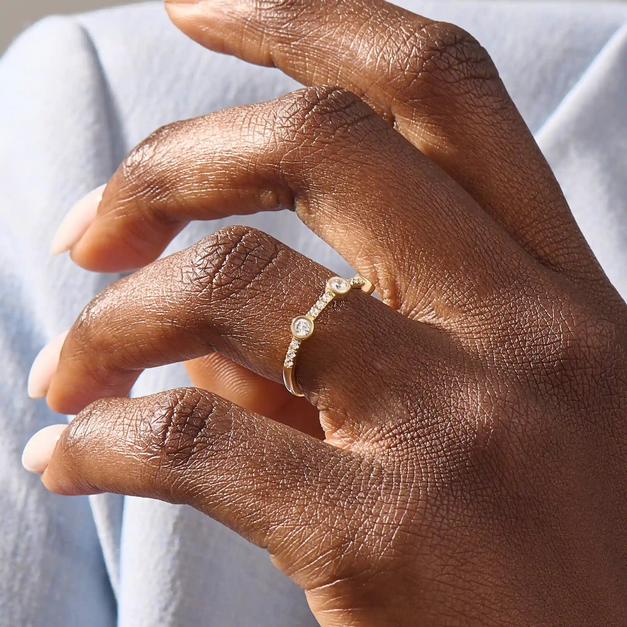 Model wears a 14k solid gold half-eternity stacking ring with three bezel moissanites. Elegant and perfect for layering.
