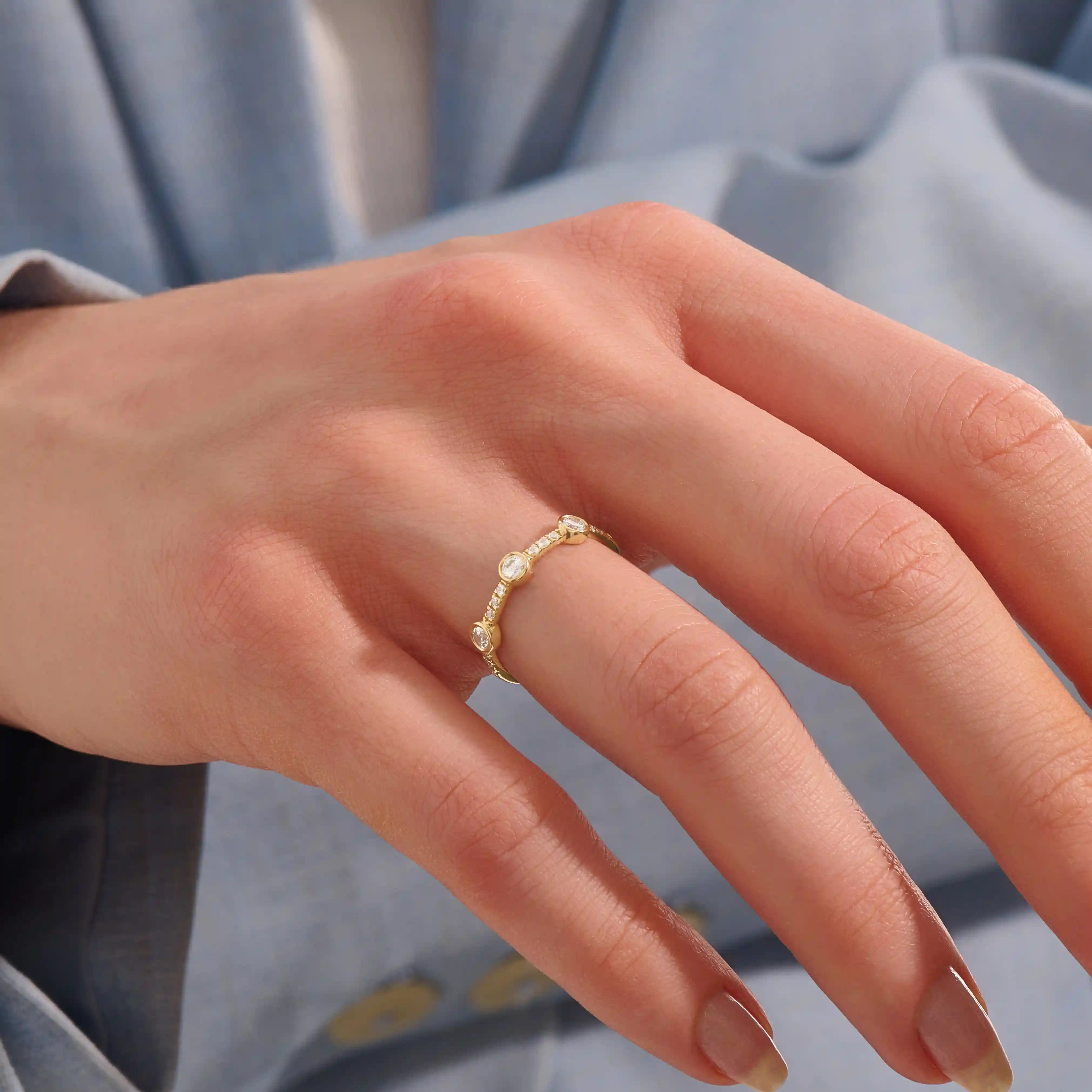 Model wears a 14k solid gold half-eternity stacking ring with three bezel moissanites. Elegant and perfect for layering.