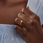 Model wears a 14k solid gold solitaire engagement or promise ring with a small flower motif. Elegant and subtle design for women’s daily wear or special occasions.