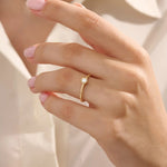 Model wears a 14k solid gold solitaire engagement or promise ring with a small flower motif. Elegant and subtle design for women’s daily wear or special occasions.