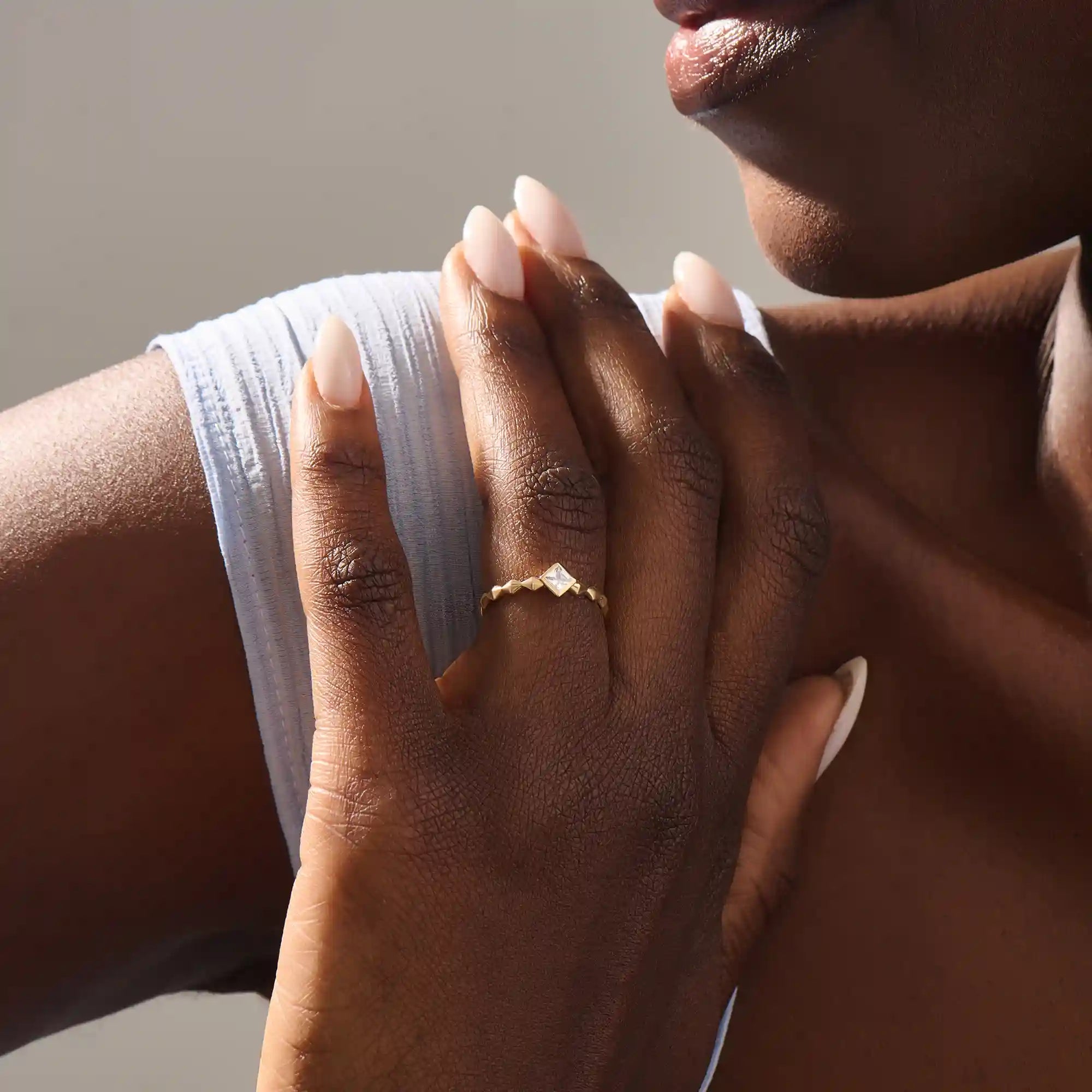 Model wears a bezel set princess square cut solitaire engagement ring in 14k solid gold. Minimalist and timeless bridal style.