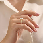 Model wears a chunky solitaire oval moissanite engagement ring in 14k solid gold. Minimalist yet bold bridal style.