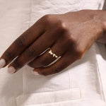 Model wears a curved 14k gold nesting ring with scattered moissanites. A delicate stacking piece that adds soft brilliance to any ring stack.