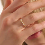 Model wears a curved 14k gold nesting ring with scattered moissanites. A delicate stacking piece that adds soft brilliance to any ring stack.