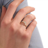 Model wears a curved gold ring adorned with baguette moissanites in an arch design. Sleek and contemporary, perfect for layering with solitaires.