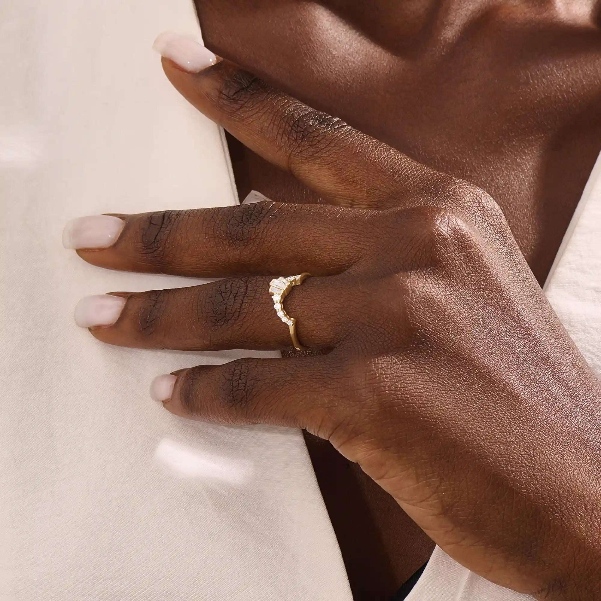 Model wears a curved gold ring adorned with baguette moissanites in an arch design. Sleek and contemporary, perfect for layering with solitaires.