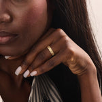 Model wears a dainty 14k gold daisy band with sparkling moissanites. A feminine statement ring with a bold yet romantic look.