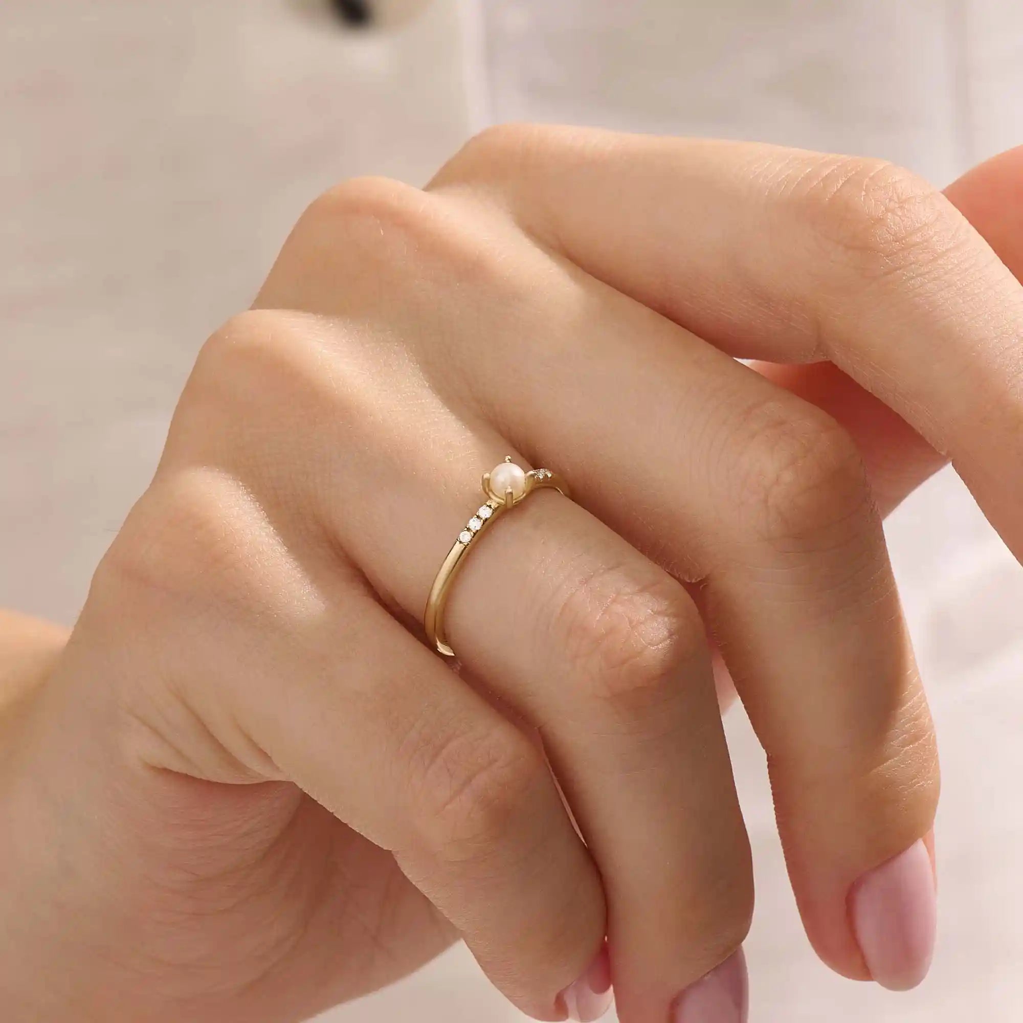 Model wears a dainty 14k gold promise ring with a small pearl centerpiece. A timeless and feminine symbol of love and commitment.