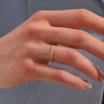 Model wears a dainty curved 14k gold ring featuring a twisted band detail. Ideal as a nesting ring or part of a minimalist stack.