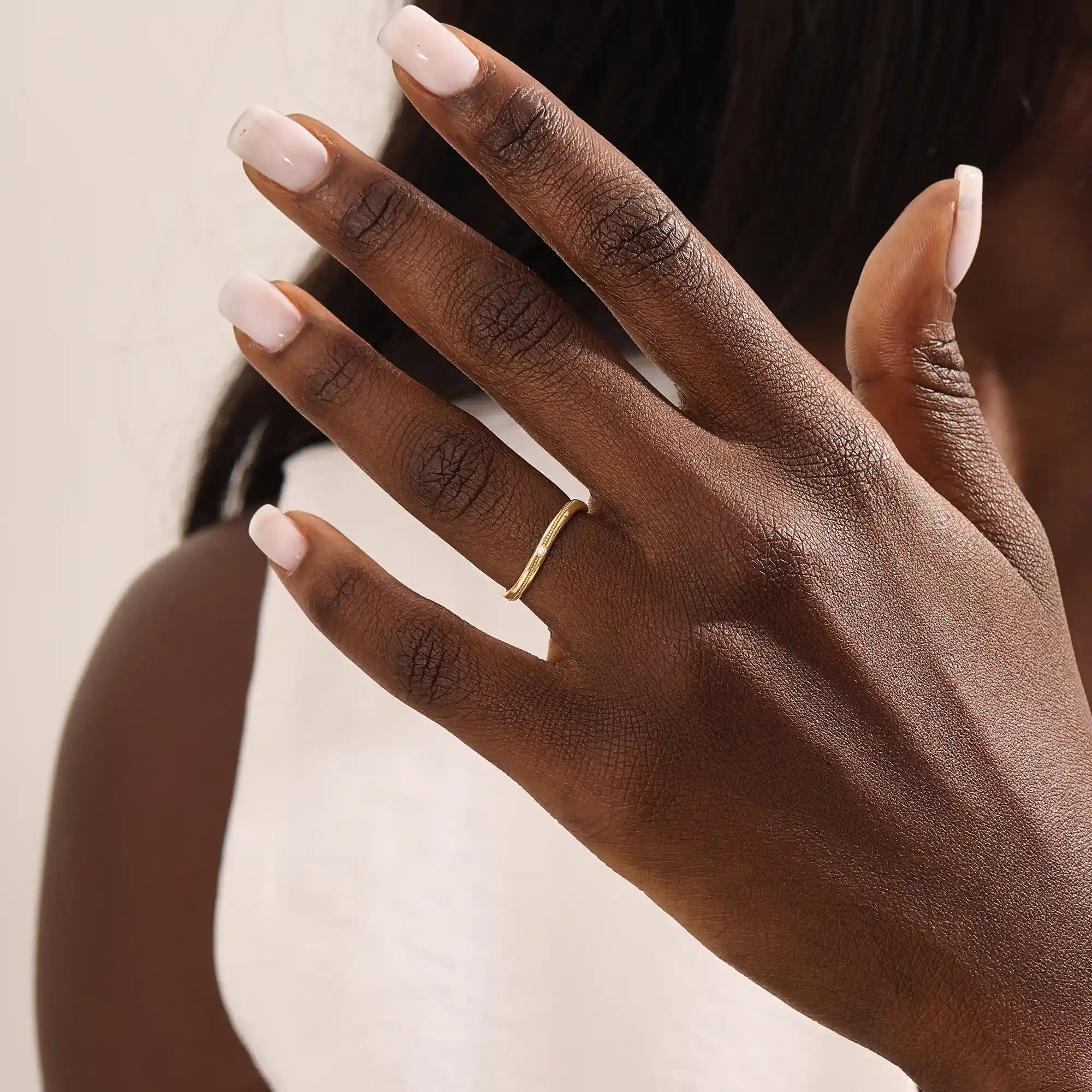 Model wears a dainty curved gold ring with beaded texture and a tiny moissanite. Minimalist and feminine, ideal for layering.