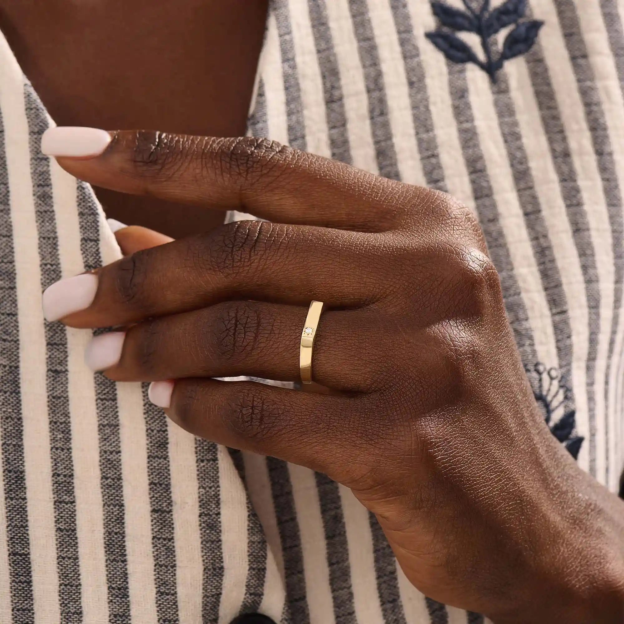 Model wears a simple 14k gold pinky signet ring with a solo moissanite accent. A contemporary and elegant piece for subtle statement style.