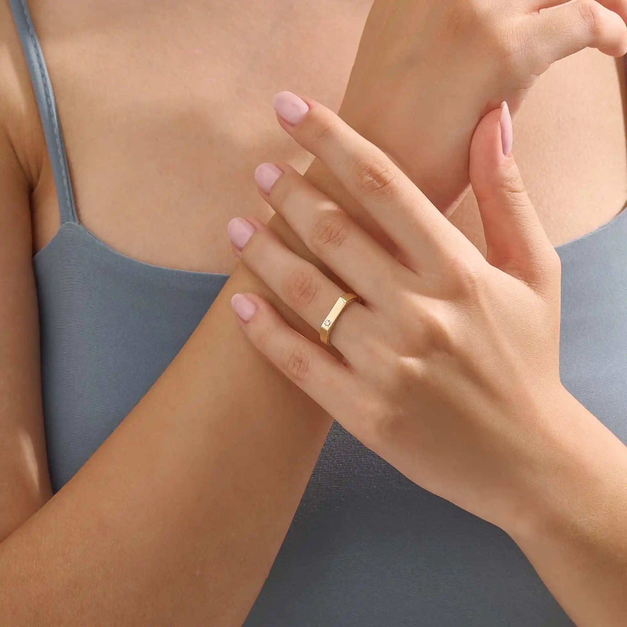 Model wears a simple 14k gold pinky signet ring with a solo moissanite accent. A contemporary and elegant piece for subtle statement style.