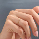 Model wears a simple 14k gold promise ring featuring a small bezel-set moissanite. A subtle and elegant symbol of commitment.