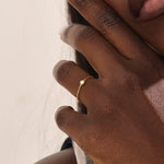 Model wears a simple 14k gold promise ring featuring a small bezel-set moissanite. A subtle and elegant symbol of commitment.