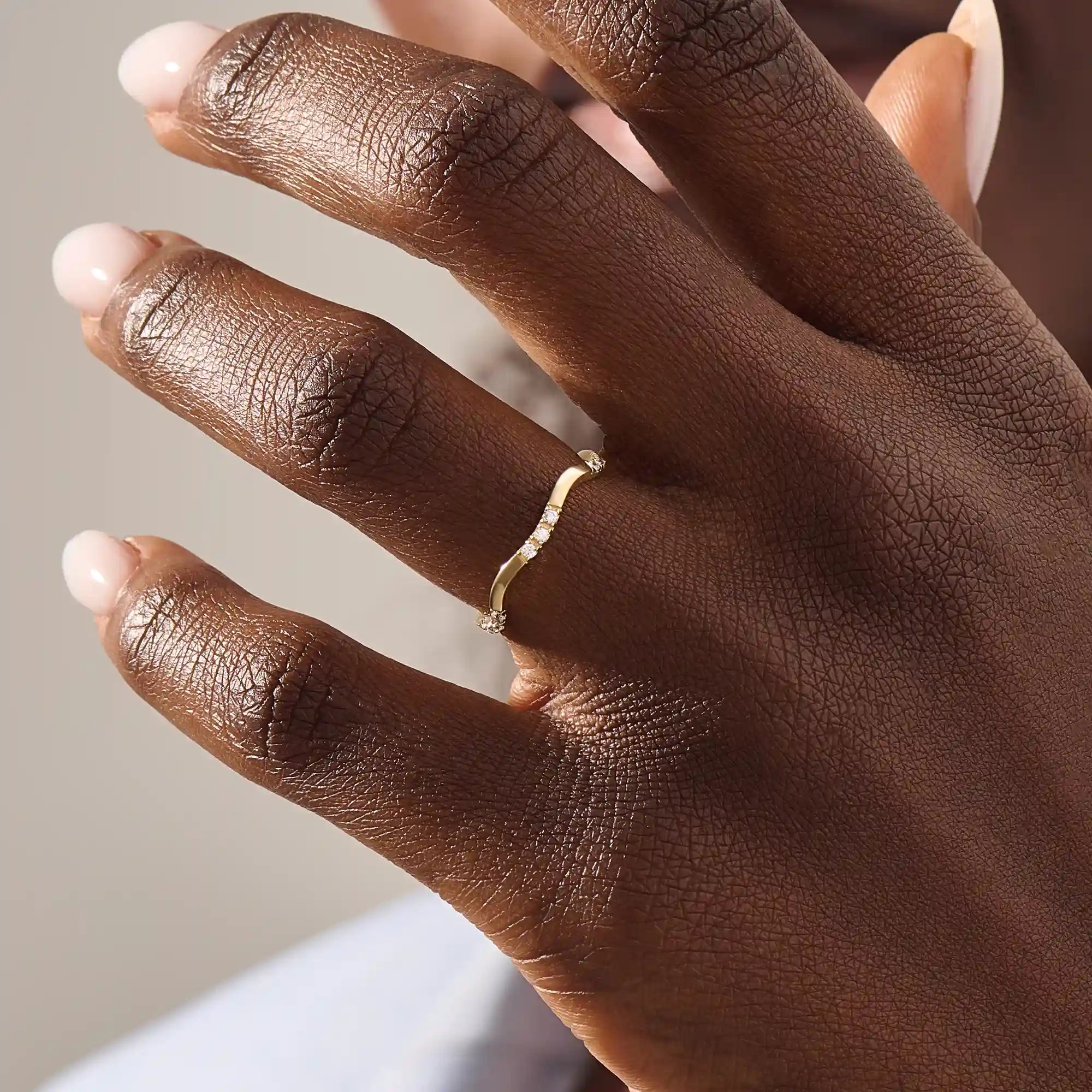 Model wears a slim 14k gold curvy band ring adorned with small moissanites. Perfect for layering or wearing solo as a subtle statement.