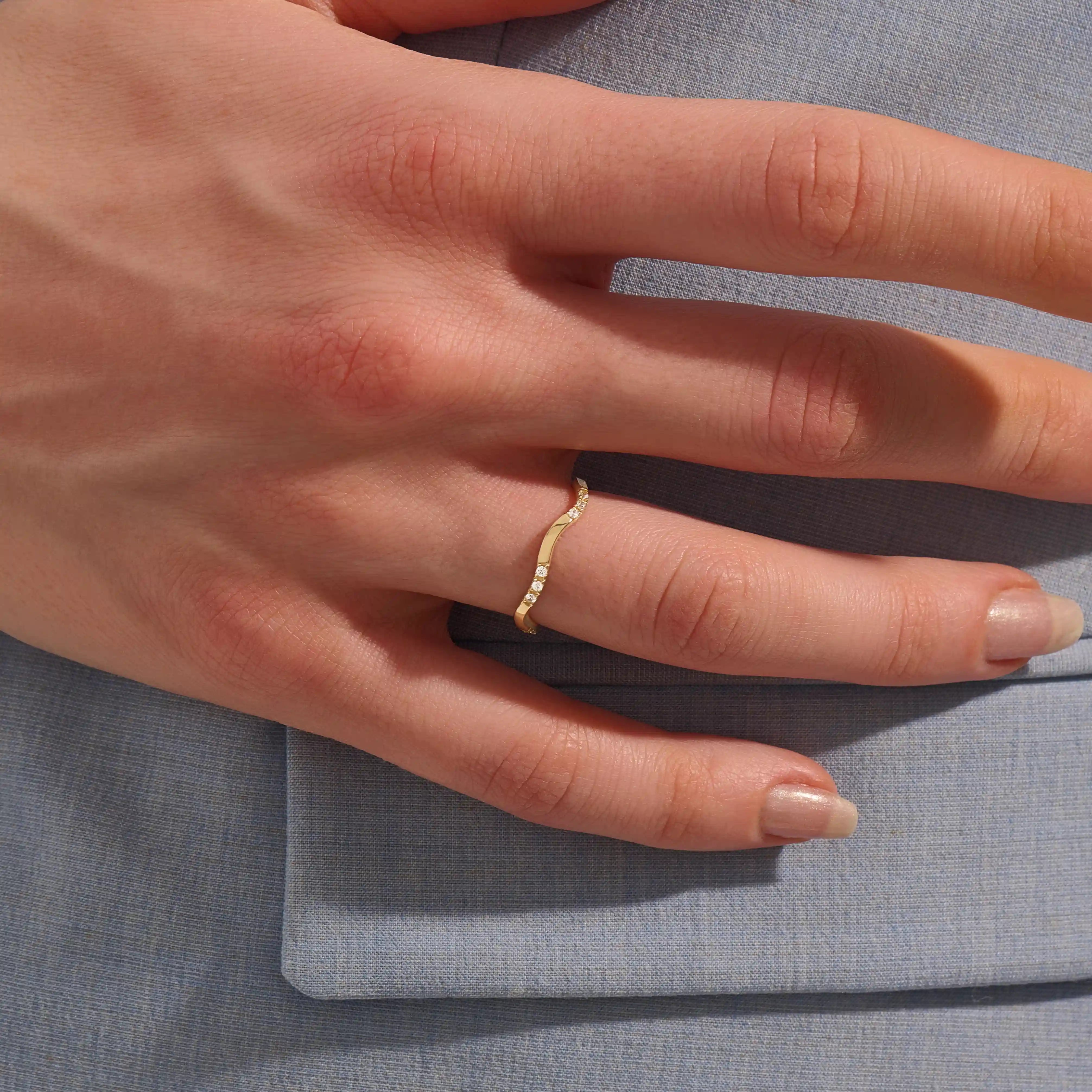 Model wears a slim 14k gold curvy band ring adorned with small moissanites. Perfect for layering or wearing solo as a subtle statement.