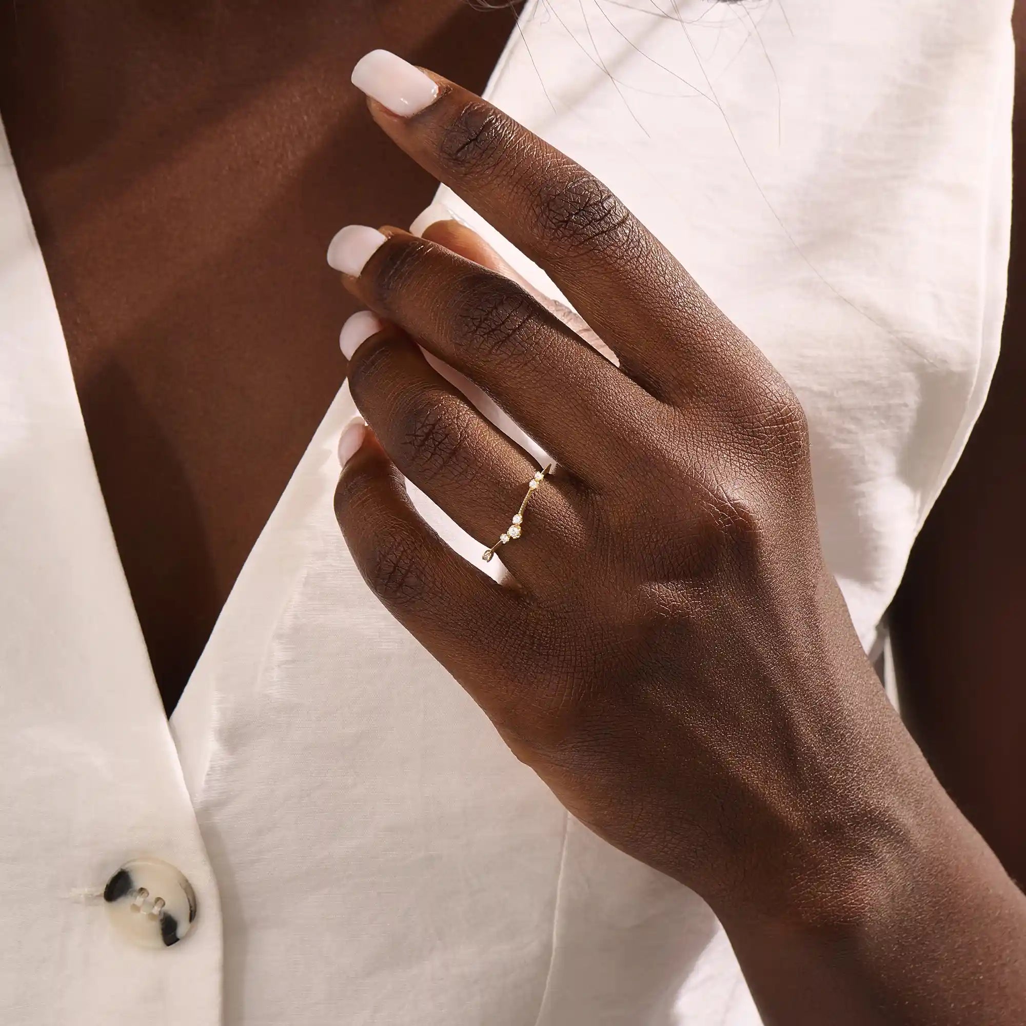 Model wears a slim vintage-style curved ring with moissanites on a delicate milgrain band. A refined stacking piece with intricate craftsmanship.