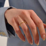 Model wears a slim vintage-style curved ring with moissanites on a delicate milgrain band. A refined stacking piece with intricate craftsmanship.