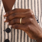 Model wears a striking 14k gold eternity ring with linked circle motifs. Perfect as a meaningful band or a modern statement ring.