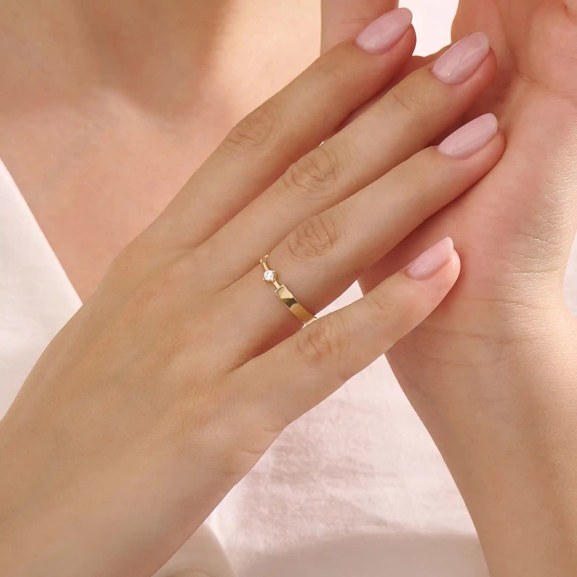 Model wears a uniquely designed 14k gold promise ring with a solo moissanite centerpiece. A stylish and meaningful symbol of commitment.