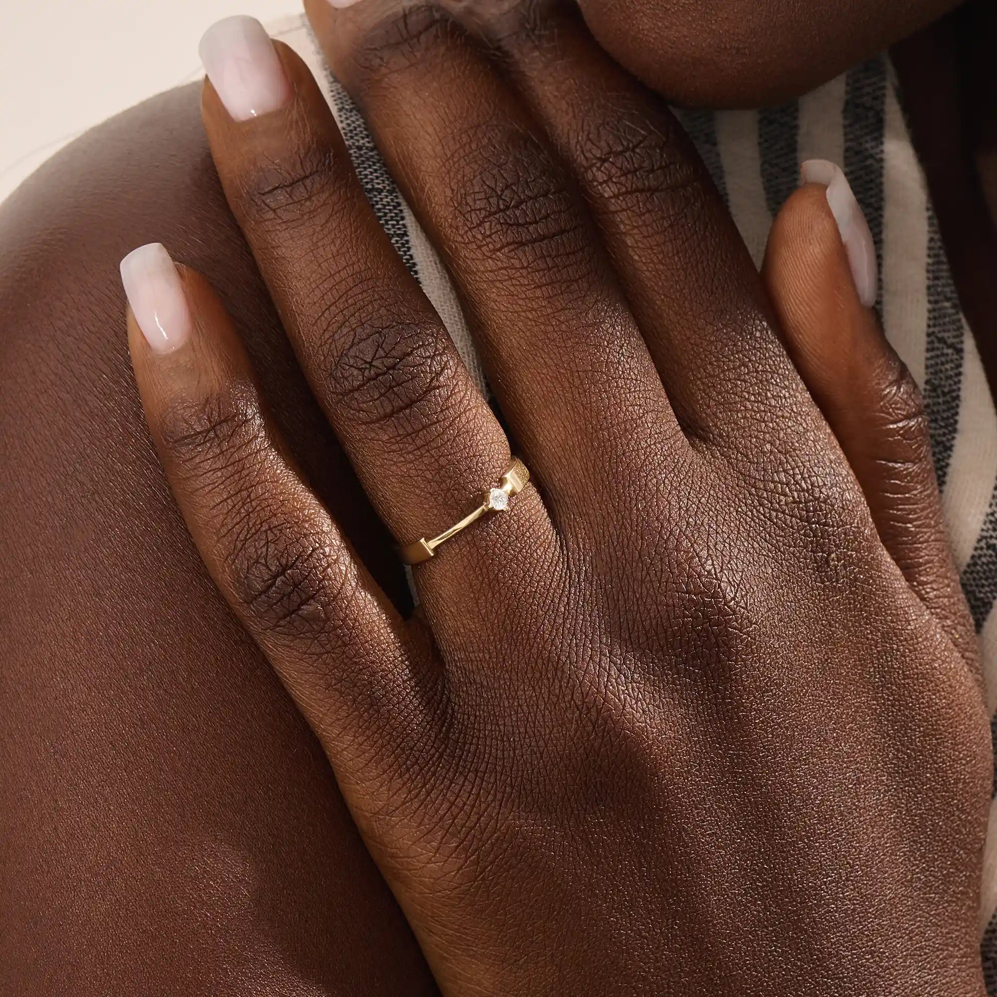 Model wears a uniquely designed 14k gold promise ring with a solo moissanite centerpiece. A stylish and meaningful symbol of commitment.