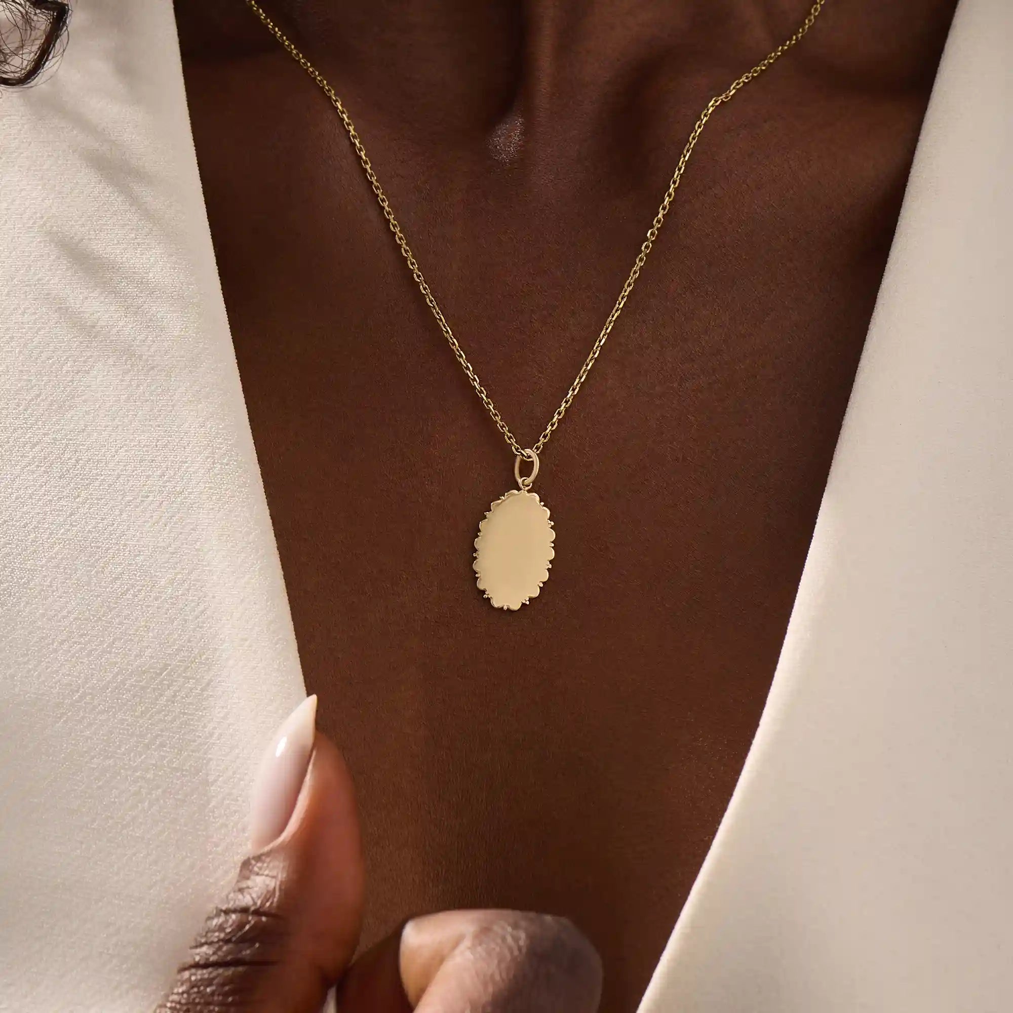 Model wears an oval plain pendant necklace in 14k gold, ideal for personal engravings. A sleek and versatile everyday accessory.